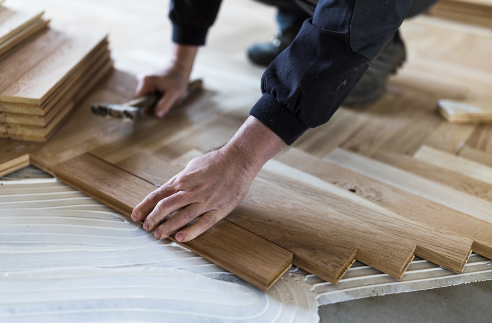 Experienced,worker,installing,parquet,boards,in,glue,in,new,house